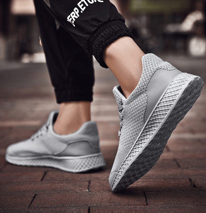Man wearing lightweight mesh men's outdoor training shoes, gray tennis shoes, showcasing breathable air mesh and durable rubber sole.
