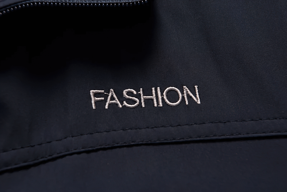 Close-up of stylish black sports jacket with "Fashion" embroidery detail, showcasing elegance and modern design for outdoor wear.
