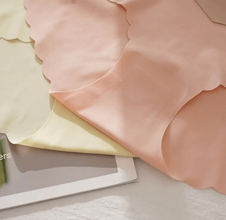 Lightweight seamless low waist panties in pink and yellow lay elegantly on a magazine, showcasing breathable fabric and stylish design.