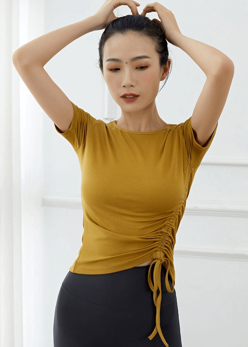 Woman wearing a lightweight sporty elastic women's T-shirt with side tie, perfect for yoga. Stylish, breathable, and comfortable fitness wear.