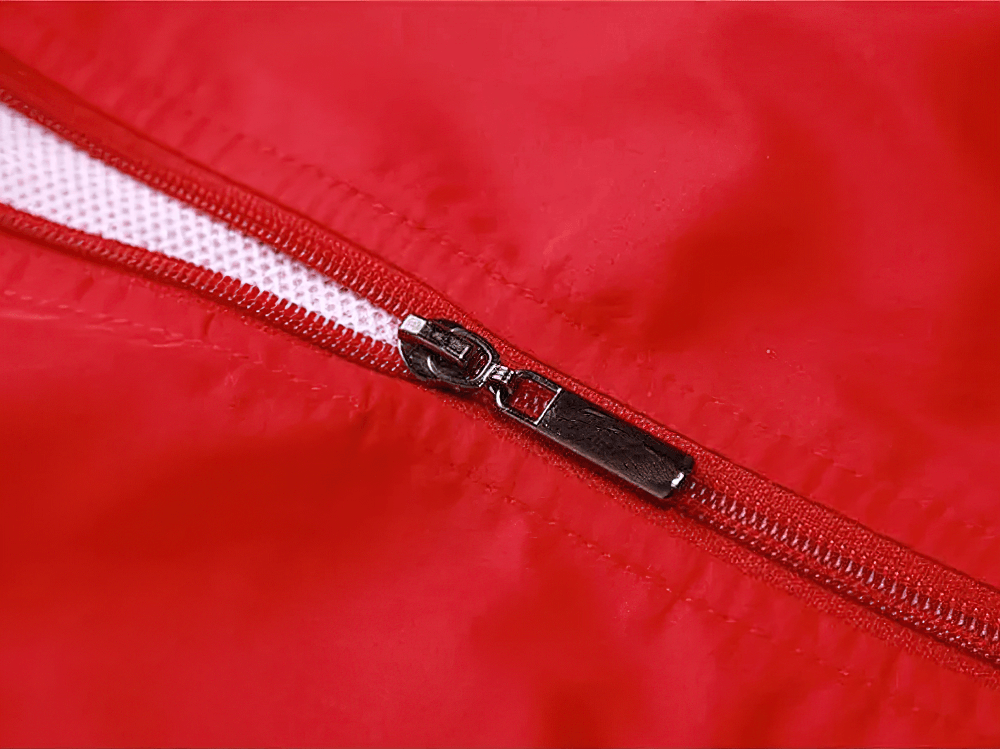 Close-up of red tracksuit zipper with breathable mesh lining, showcasing sleek modern design and durable polyester fabric.