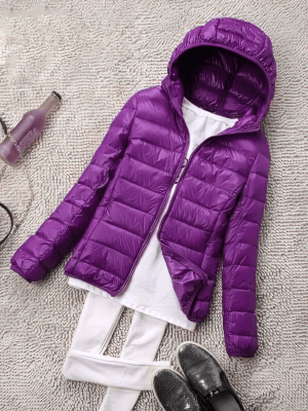 Purple lightweight women's jacket with hooded zipper, slim fit, displayed with white top and pants on textured grey background.