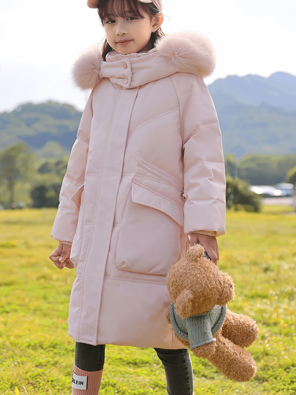 Girl wearing Long Down Coat with Hood and Faux Fur Trim - SF3525, pink puffer jacket with big pockets in a winter landscape.