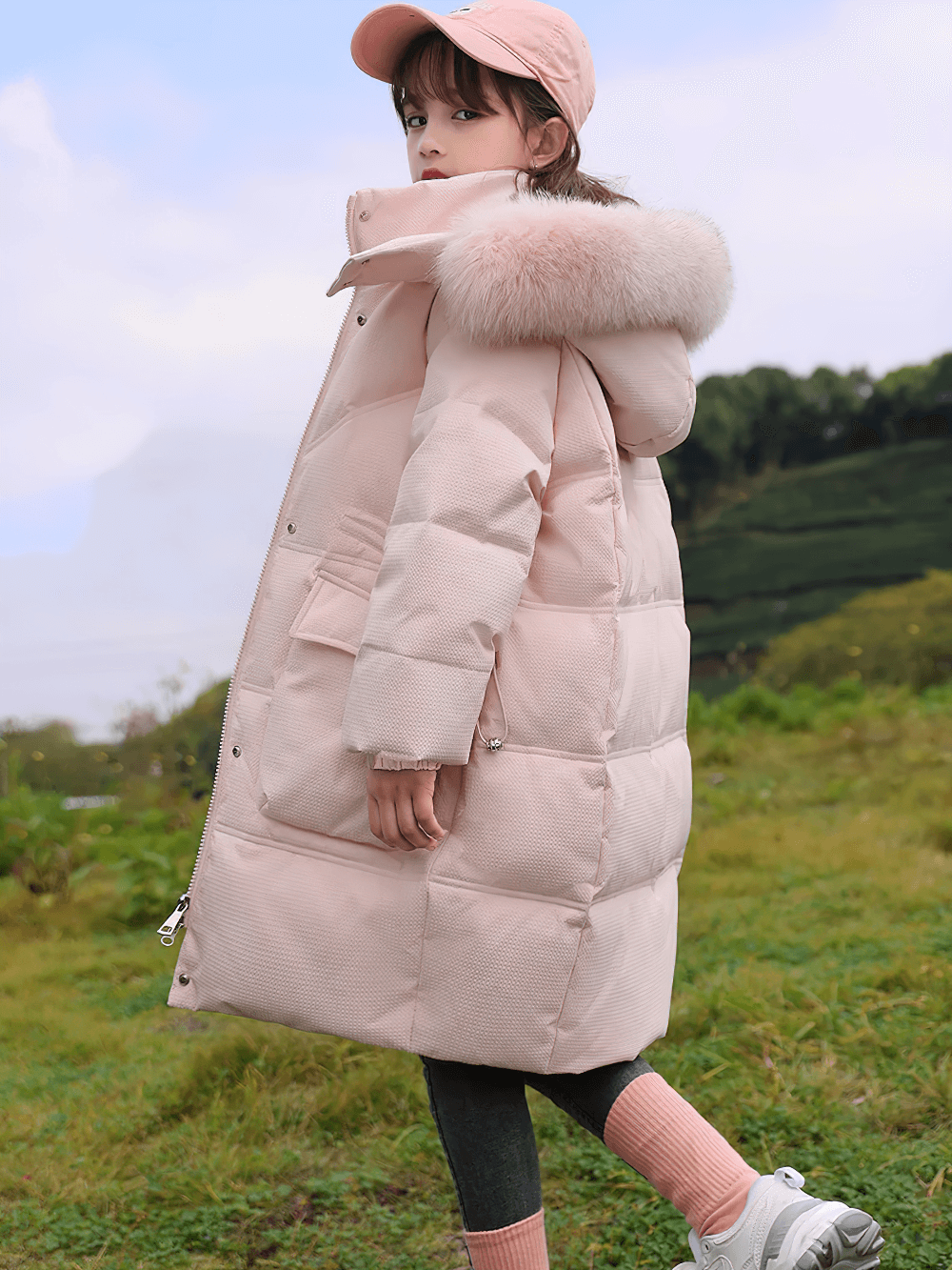 Girl wearing Long Down Coat with Hood and Faux Fur Trim - SF3525, standing in a grassy field, showcasing winter warmth and style.
