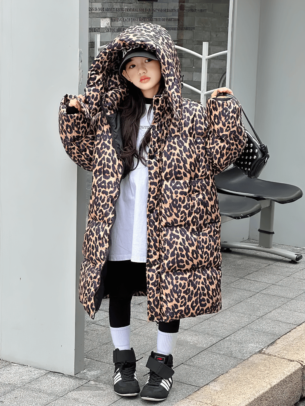 Girl wearing Long Leopard Print Hooded Puffer Coat - SF3527, showcasing trendy winter style with animal print design and oversized hood.