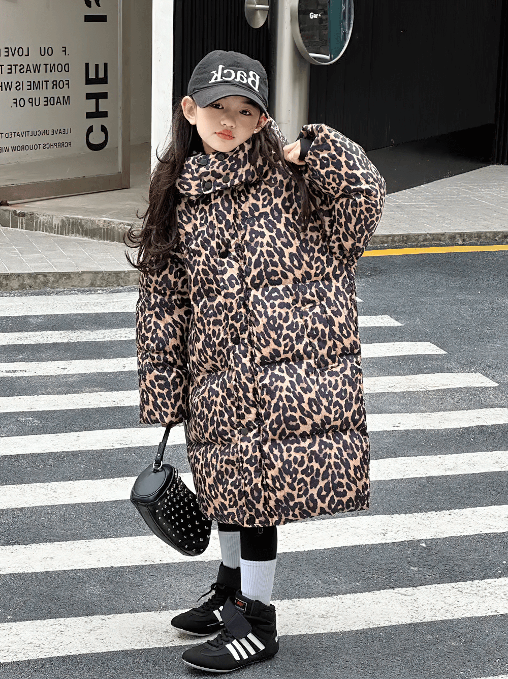 Girl wearing Long Leopard Print Hooded Puffer Coat - SF3527 standing on a crosswalk, showcasing the stylish animal print jacket for winter.