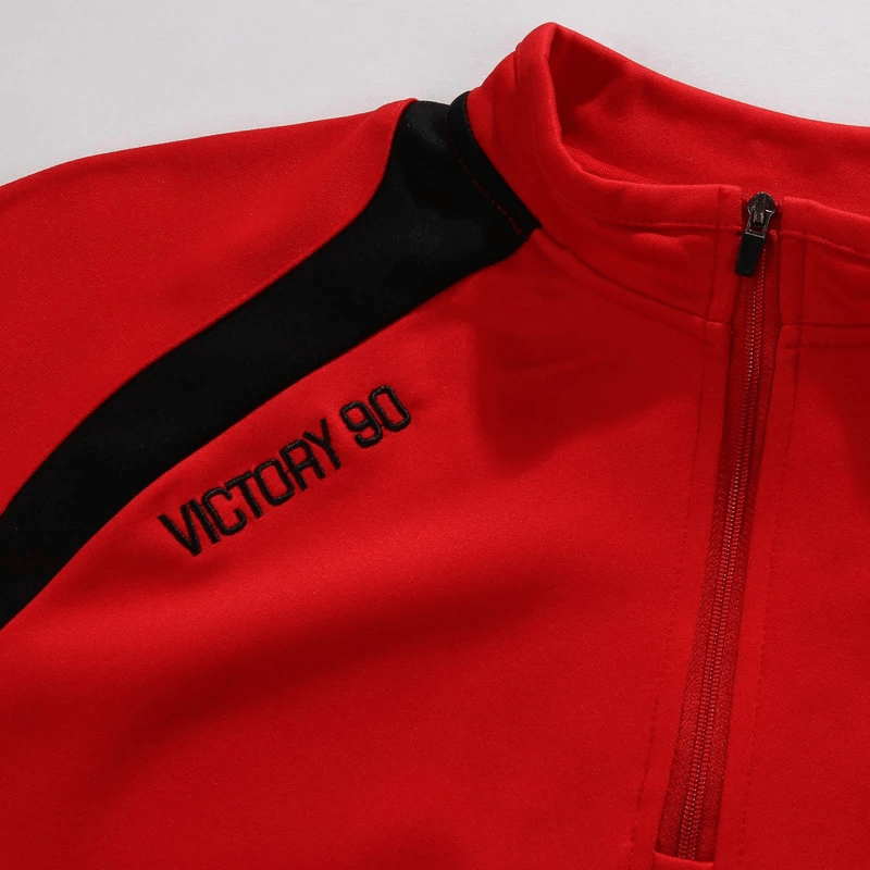 Close-up of a red Victory 90 sports top with black accents and zip collar, perfect for athletic wear and outdoor activities.