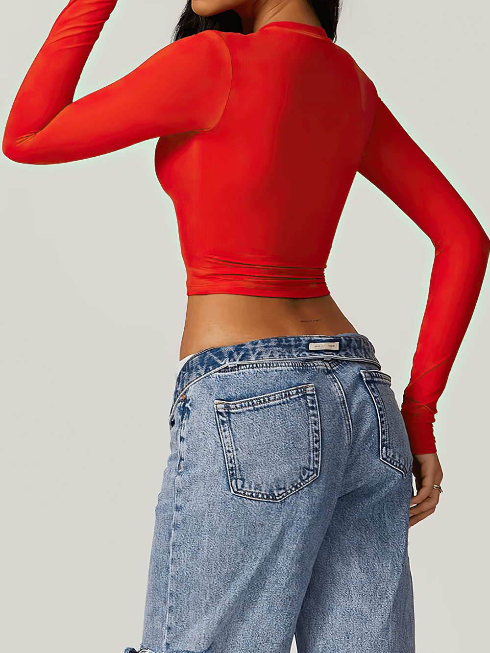 Woman wearing vibrant red long-sleeve sports crop top with jeans, perfect for yoga and fitness workouts.