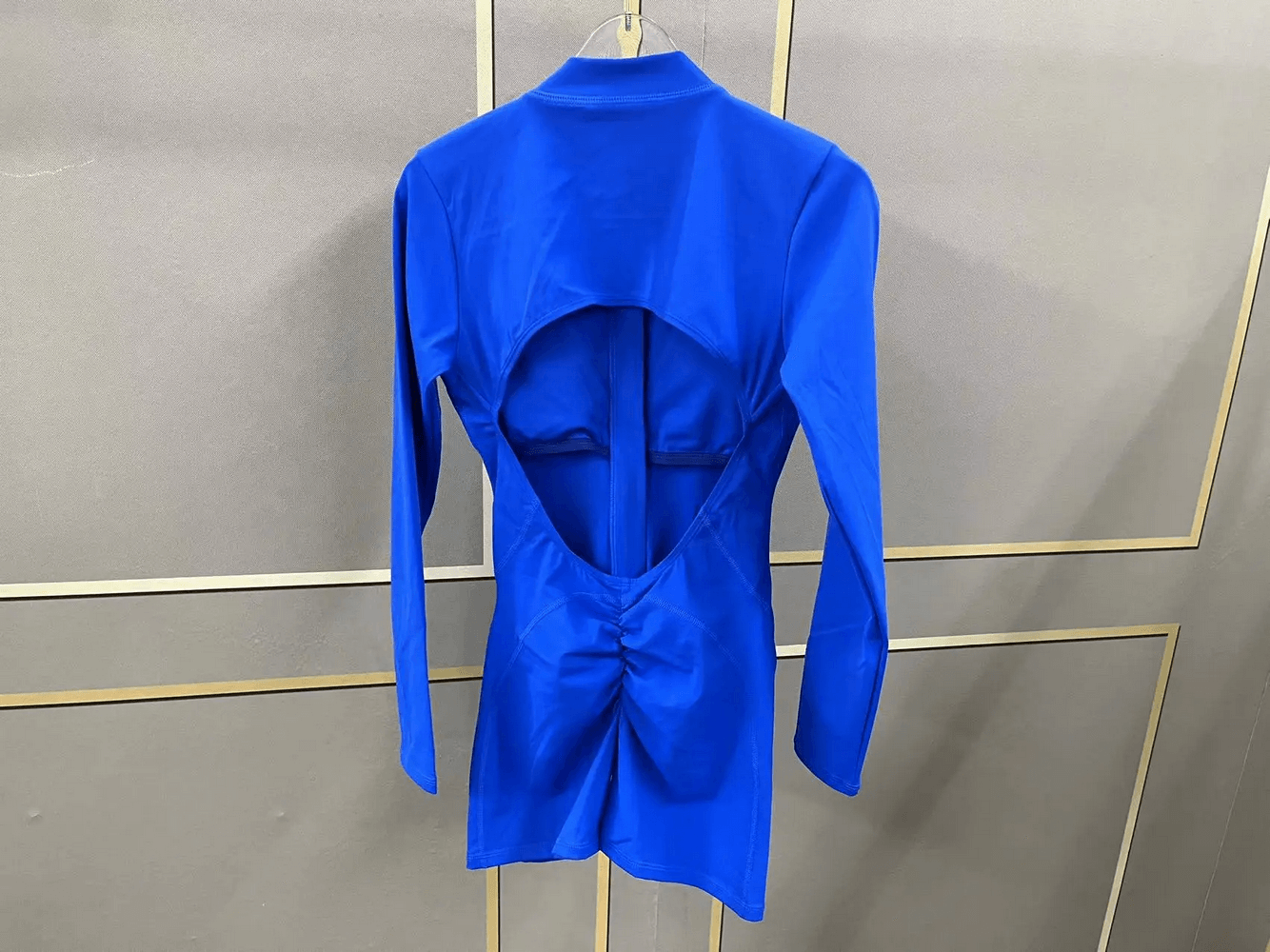 Vibrant blue long-sleeved open-back activewear romper with full-zip closure, ideal for yoga or gym sessions.