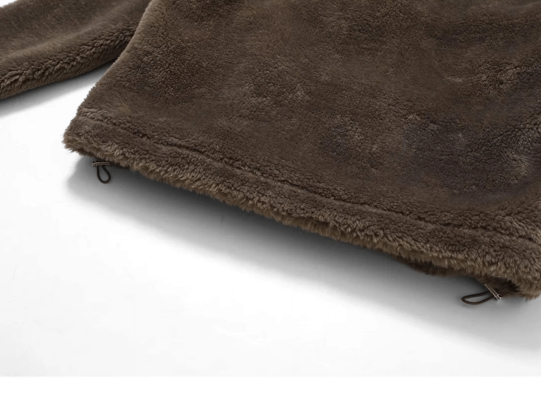 Close-up of brown lamb fleece jacket with adjustable hem, showcasing soft texture and quality stitching for outdoor activities.