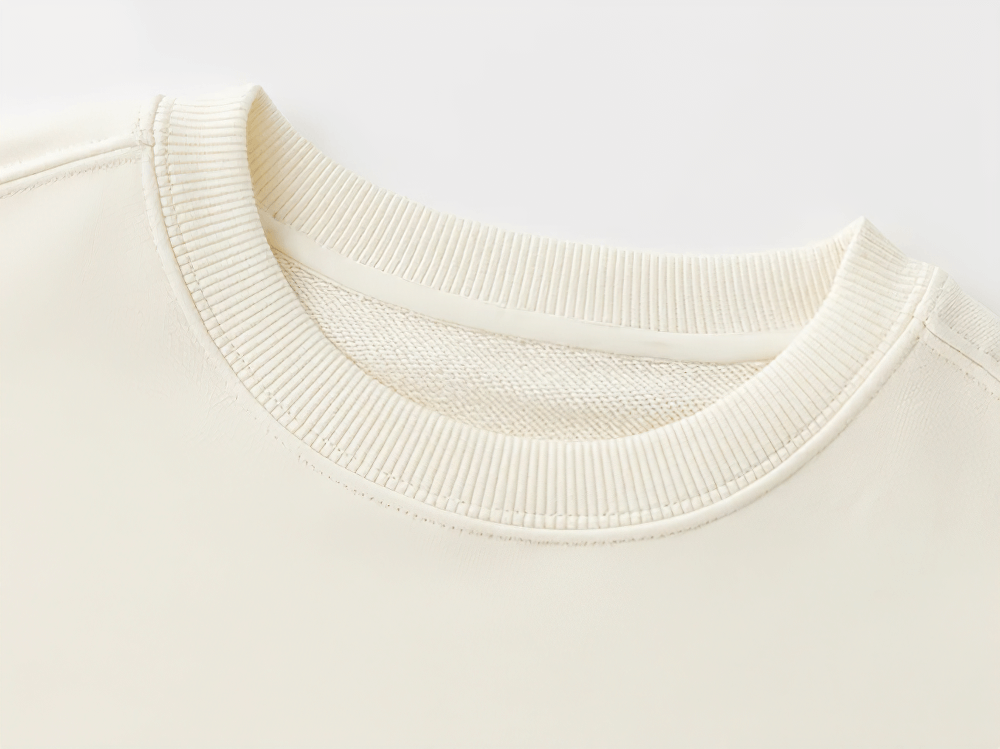 Close-up of a soft cream sweatshirt collar, showcasing ribbed detailing.