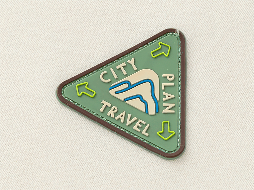 Triangular travel patch with 'City Plan Travel' and colorful arrows on a textured fabric background.
