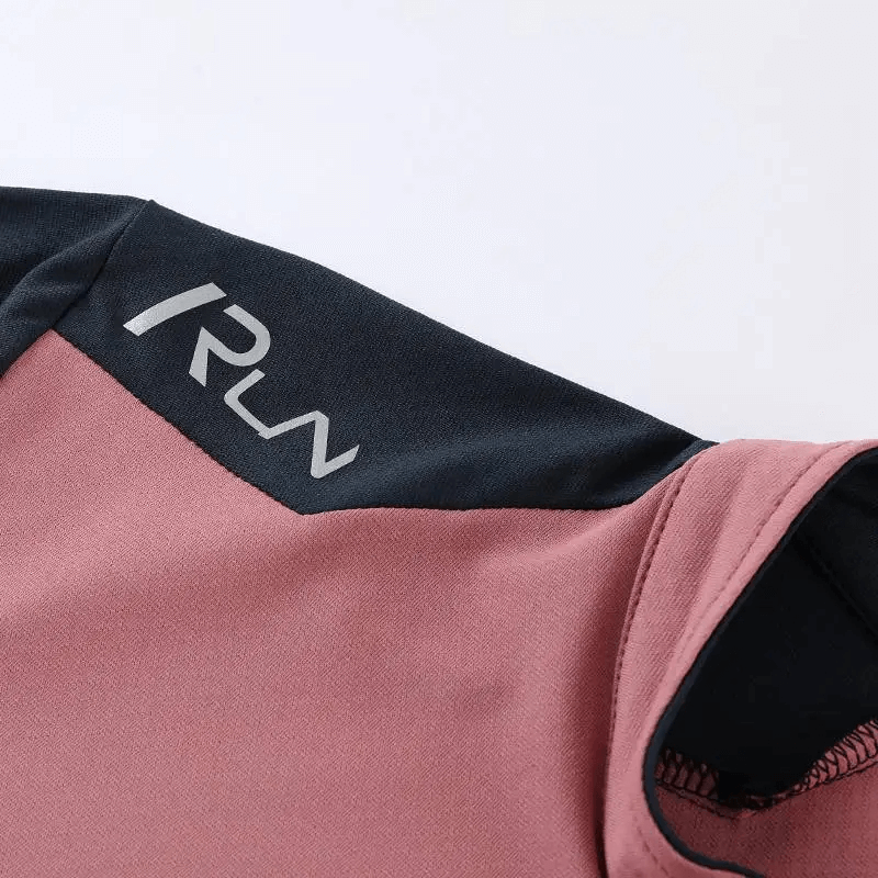 Close-up of a long sleeve black and pink running pullover with logo detail, showcasing performance design and vibrant color contrast.