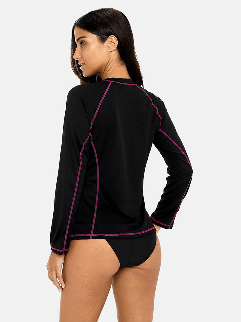 Back view of model wearing women's long sleeves surf top in black with pink stitching, providing UPF 50+ sun protection, perfect beachwear.