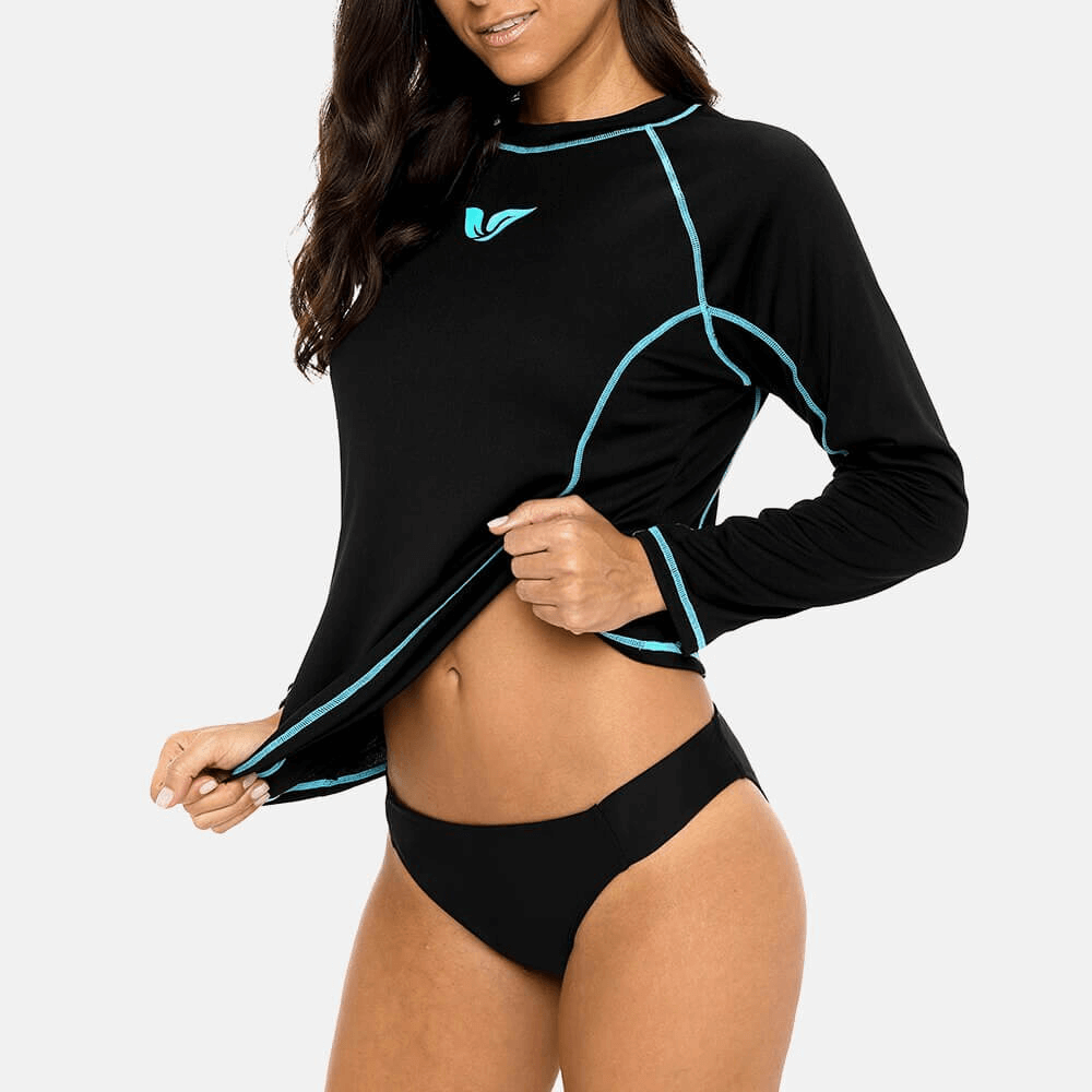 Woman modeling black long sleeves surf top UPF 50+ with turquoise seams, ideal beachwear for sun protection.