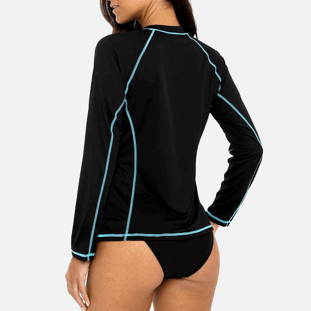 Woman wearing a black long sleeves surf top with blue trim, providing UPF 50+ protection, made from polyester. Perfect for beach activities.