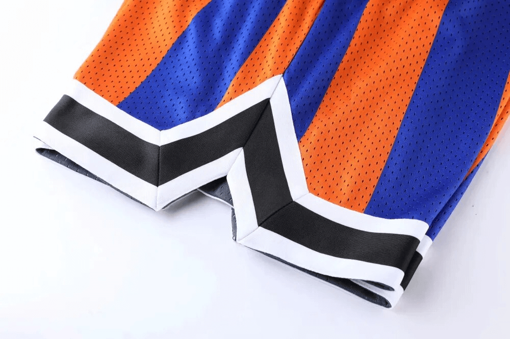 Close-up of orange and blue breathable basketball shorts with zigzag hemline design and quick dry technology for workouts.