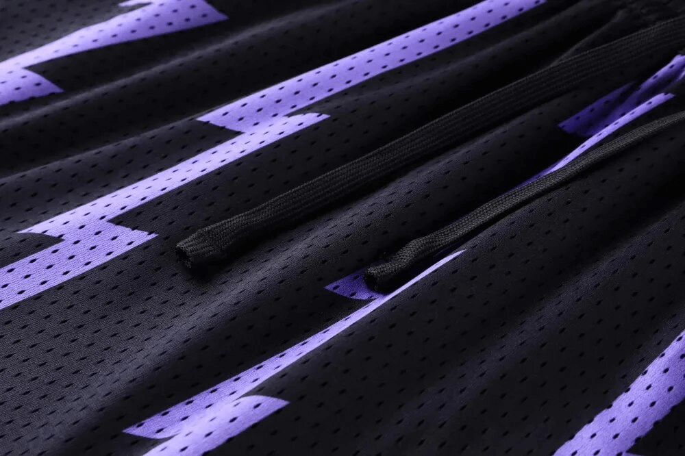Close-up of black basketball shorts with purple lightning print and drawstring, breathable fabric designed for comfort and style.