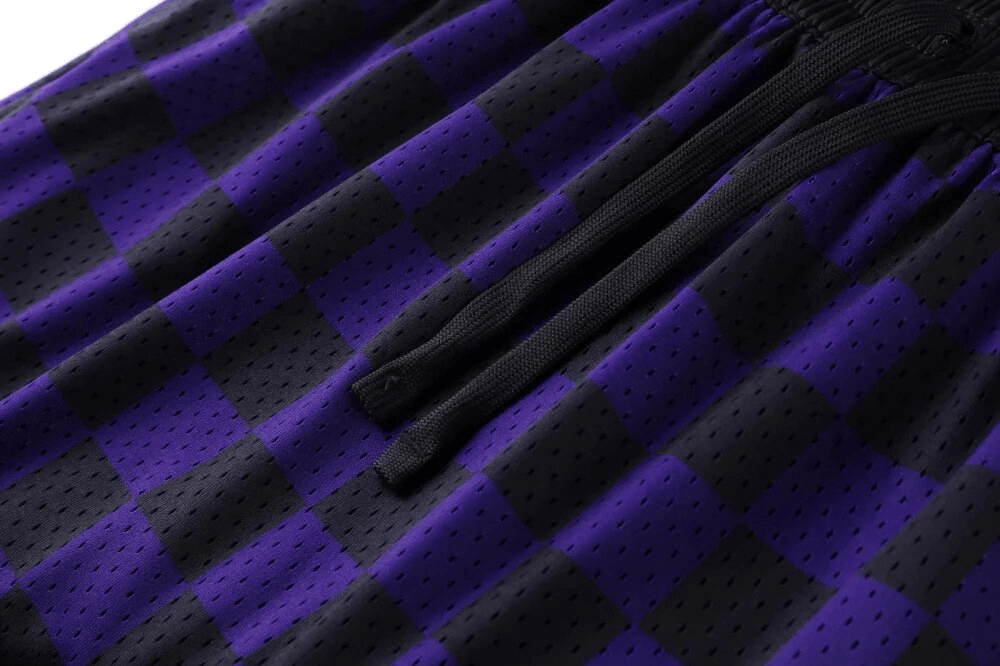 Close-up of purple and black checkered breathable basketball shorts with drawstrings, featuring quick-dry fabric for comfort and style.