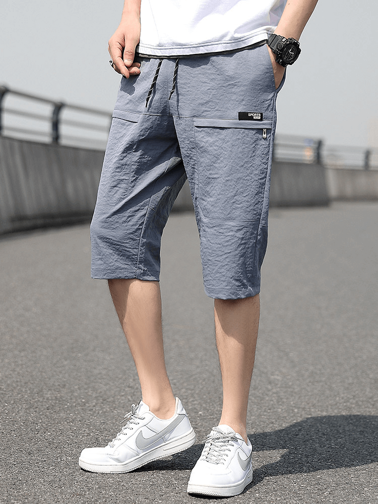 Loose breathable drawstring calf-length shorts for men in light blue, featuring pockets and comfortable fit, perfect for casual outings.