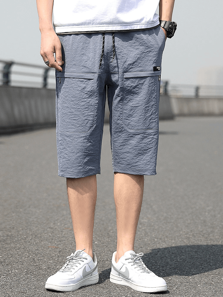 Men's loose breathable drawstring shorts in blue, calf-length, lightweight spandex and polyester, featuring pockets.