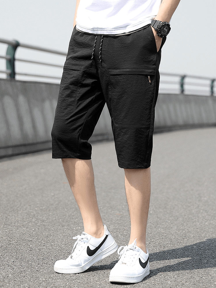 Men's loose breathable black drawstring calf-length shorts SF1351 on model with sneakers, featuring pockets for added convenience.
