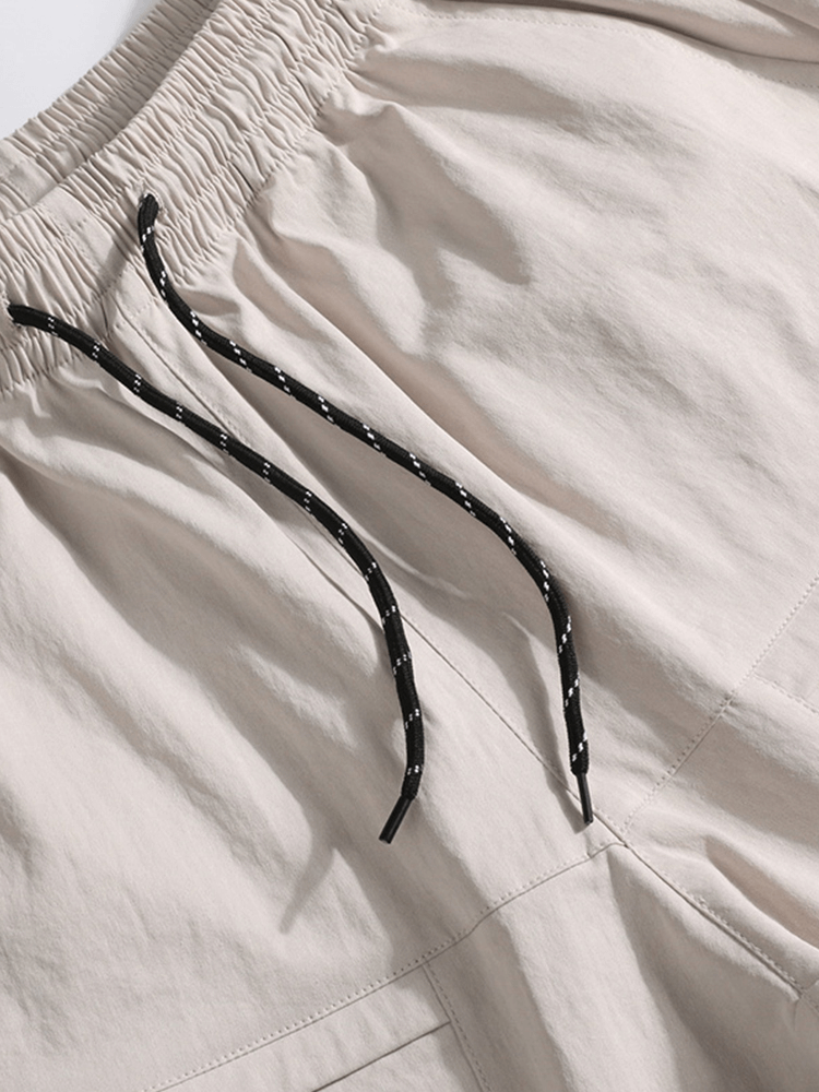 Close-up of beige breathable drawstring calf-length shorts for men with black and white drawstrings, highlighting the fabric and pocket details.