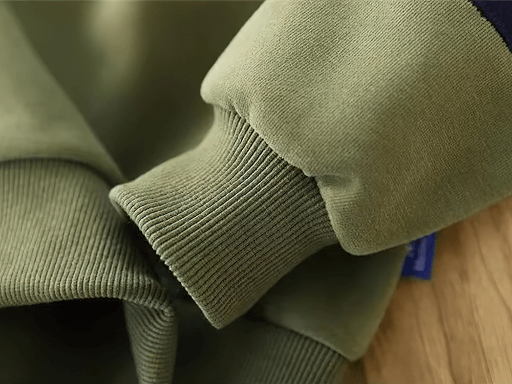 Close-up of loose cotton pullover with contrast elbow patches, showcasing soft fabric texture and ribbed cuffs.