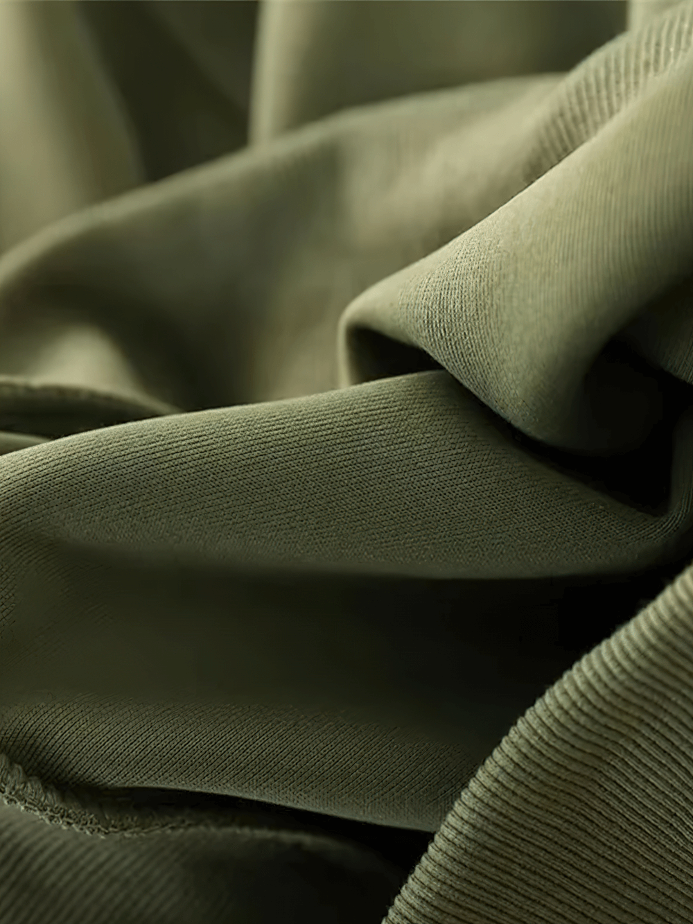 Close-up of loose cotton fabric in olive green, showcasing texture and quality