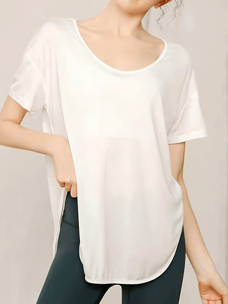 Woman wearing loose round neck solid white workout t-shirt, ideal for yoga. Comfortable, breathable fabric. Short sleeves, stylish fit.