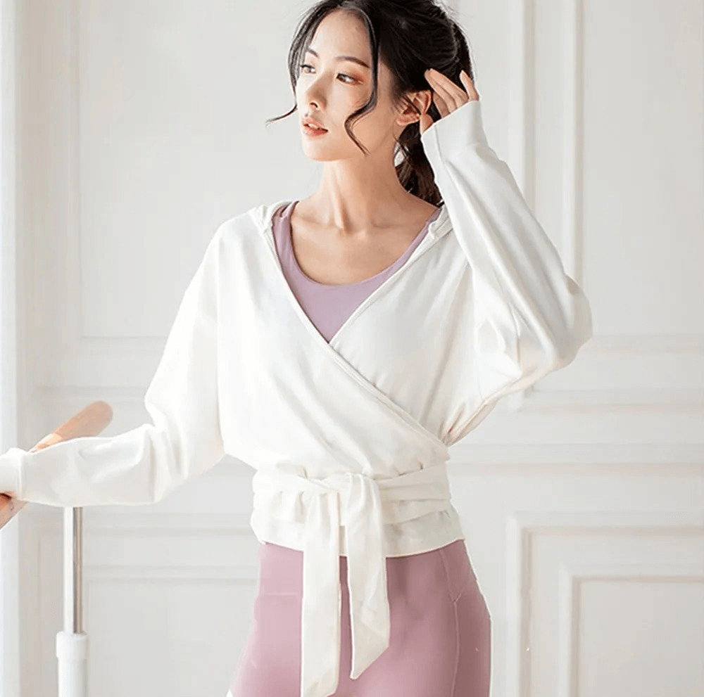 Woman wearing a loose sports top with long sleeves and tie waist, perfect for workouts. Stylish and breathable polyester design.