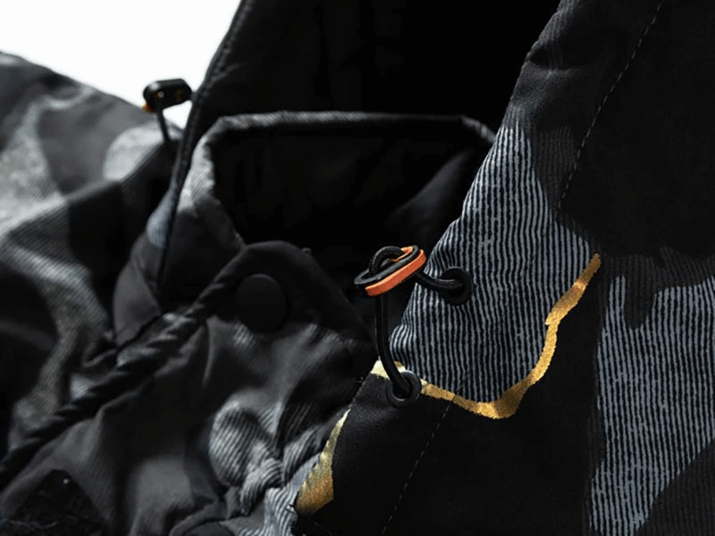 Close-up of black double-sided ski jacket with hood and patch pockets, showcasing durable, windproof fabric for winter sports.