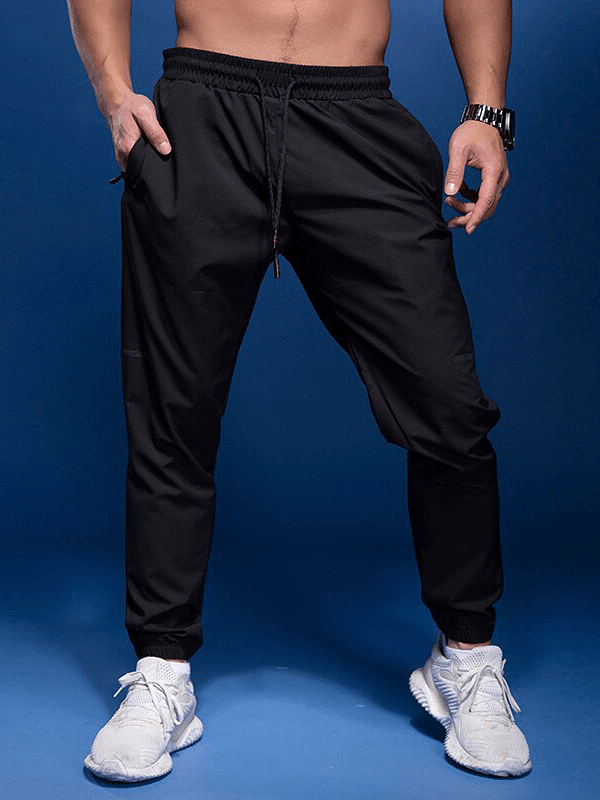 Man wearing black elastic waist sports joggers with zipper pockets, showcasing comfort and flexibility for an active lifestyle.