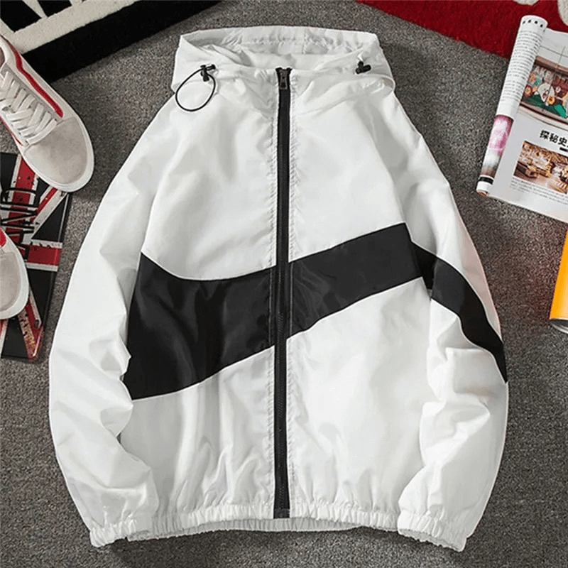 White and black patchwork hooded jacket with zipper closure on a carpeted floor with magazines.