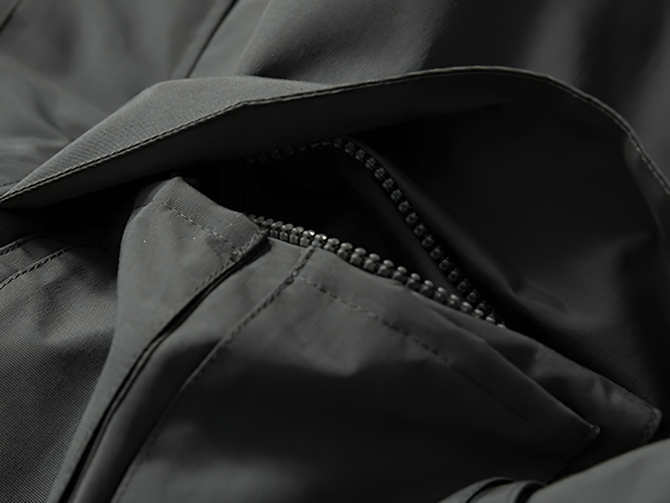 Close-up of a black multi-pocket windproof jacket with zipper, showcasing durable fabric and sleek design for outdoor adventures.