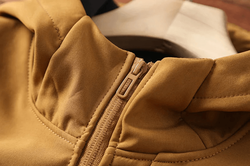 Close-up of a durable waterproof hiking jacket in tan with zipper, ideal for outdoor adventures.