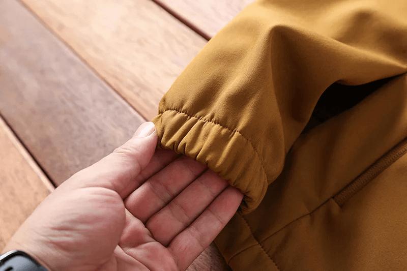 Close-up of durable waterproof jacket sleeve in mustard brown, perfect for hiking and camping.