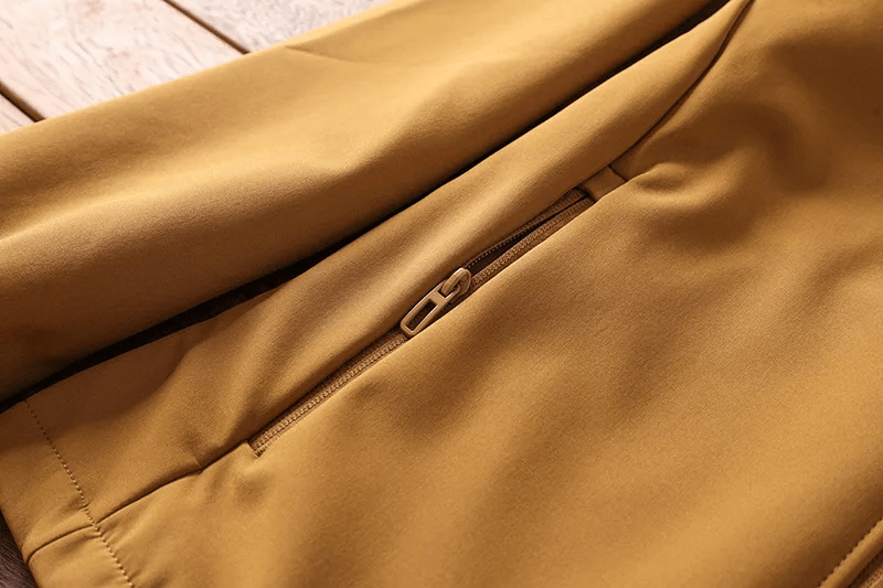 Close-up of a brown outdoor jacket with a zippered pocket, showcasing durable waterproof fabric for hiking and camping adventures.