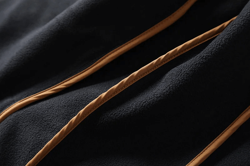 Close-up of durable polyester fabric on male outdoor hiking jacket, showing waterproof and windproof features in black and orange.