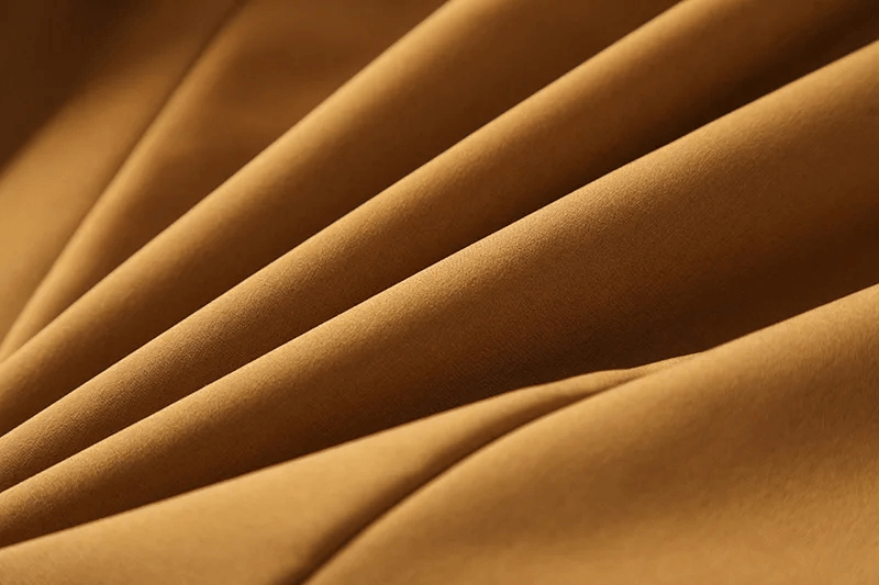 Close-up of durable polyester fabric in brown, ideal for waterproof outdoor jackets, showcasing weave and quality for hiking and camping gear.
