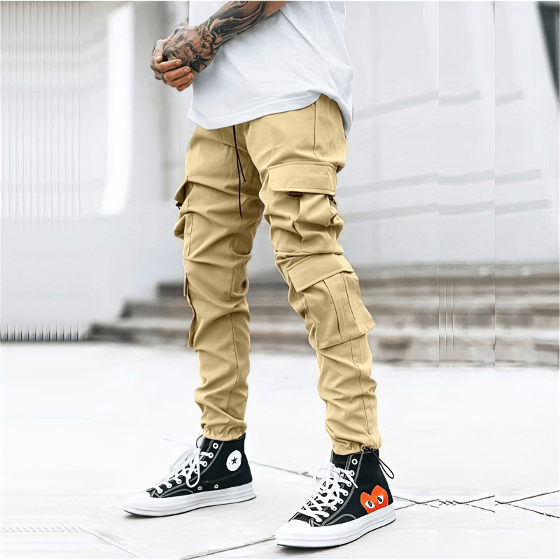 Beige male sweatpants joggers with multiple side pockets, featuring a trendy street style with black sneakers.