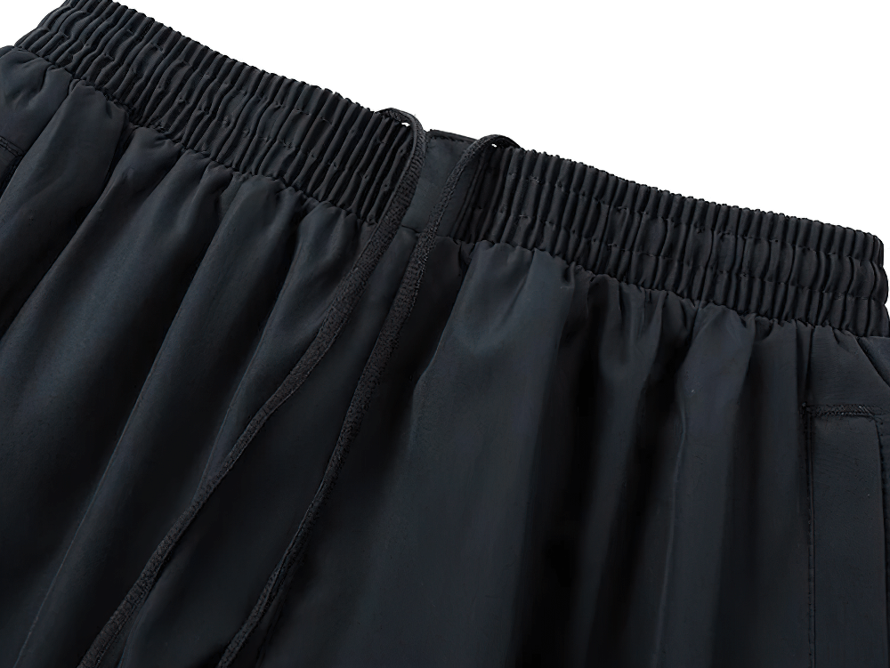 Close-up of black elastic-waist sports pants from the men's active tracksuit set, featuring stylish patchwork design.