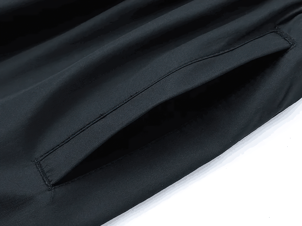 Close-up of pocket detail on men's T90 sports tracksuit with patchwork design, showing durable polyester fabric in black.