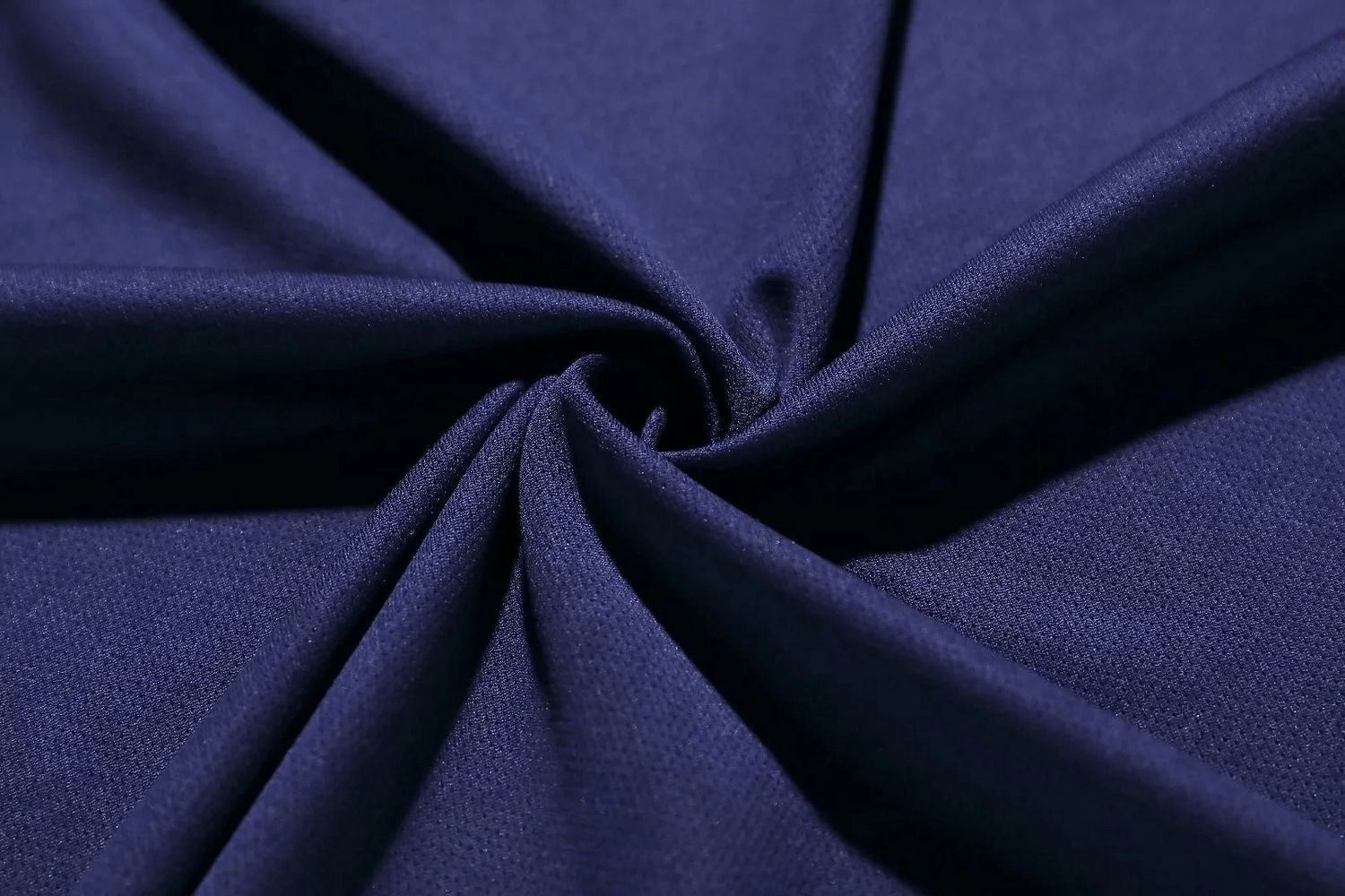 Close-up of navy blue breathable athletic fabric twisted in a swirl pattern, highlighting texture and comfort.