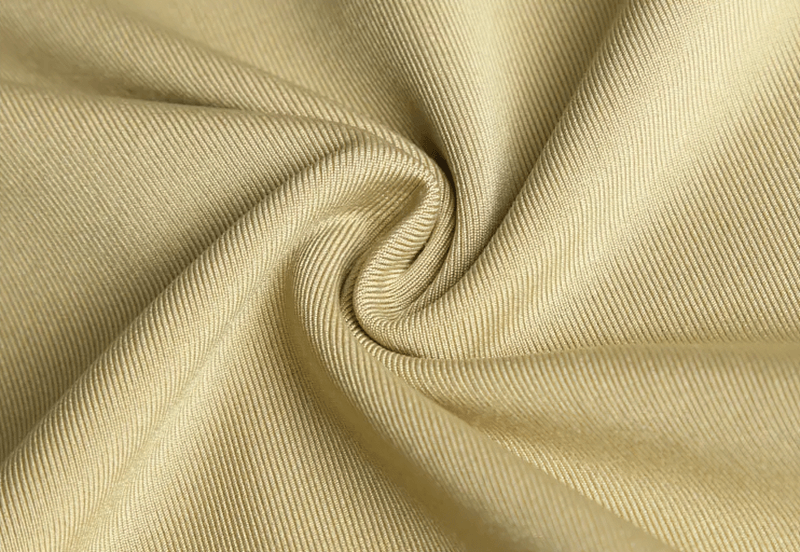 Close-up of beige breathable fabric with a twisted texture, highlighting its elasticity and softness for sports apparel.