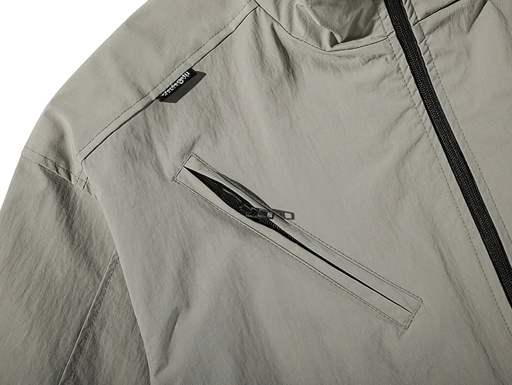 Close-up of men's loose-fit work jacket with stand collar and zippered pocket, made of durable polyester, in light gray color.