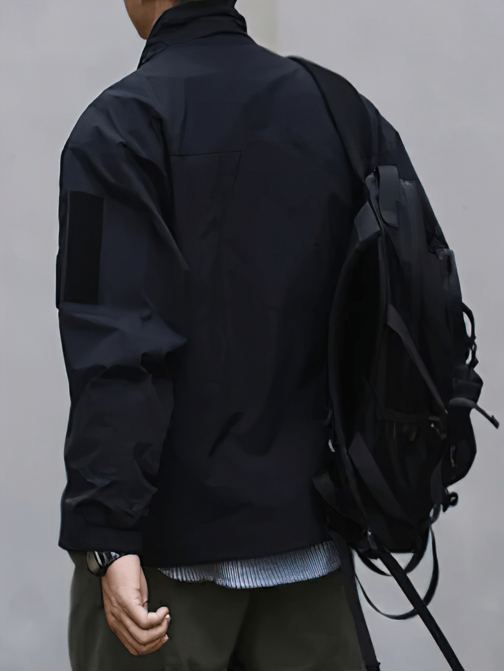 Man wearing black stand collar work jacket with backpack, showcasing loose fit and functional design for outdoor or casual activities.