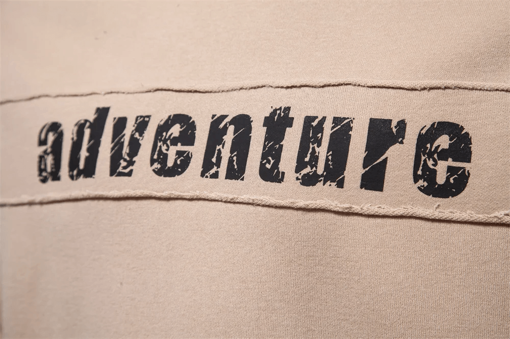 Close-up of Men's Patchwork Adventure Print Sweatshirt, beige fabric with bold black 'adventure' print, casual and trendy design.