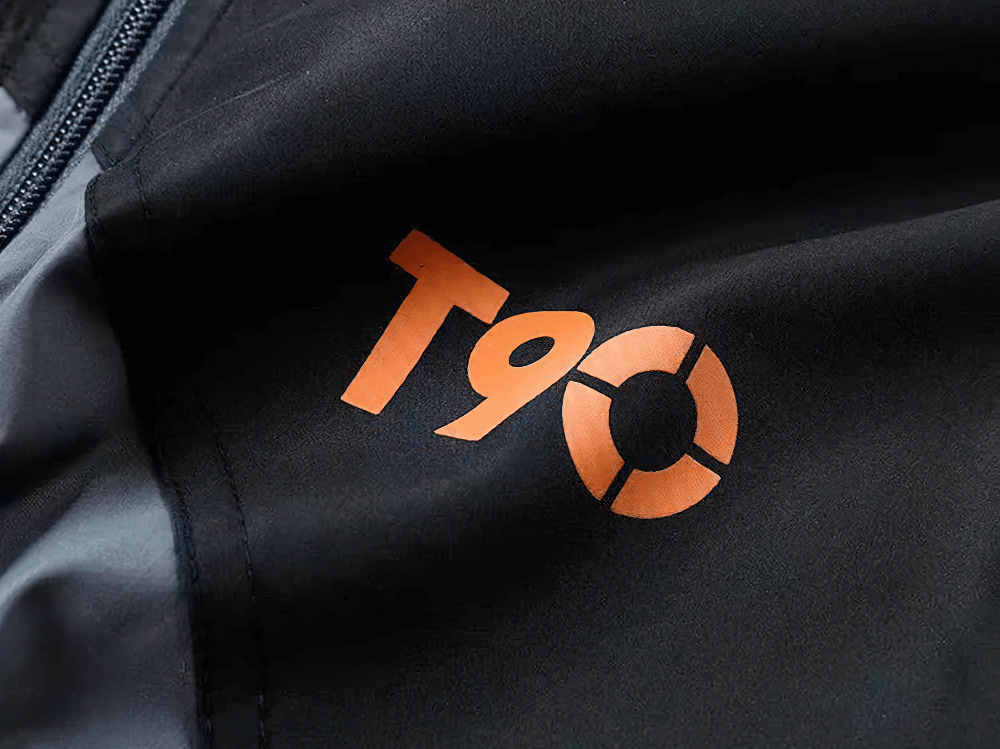 Close-up of T90 logo on Men’s Sports Tracksuit with Breathable Design, featuring bold orange accents on lightweight material.