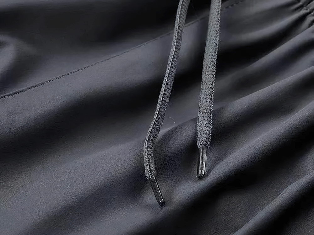 Close-up of black sports tracksuit fabric with drawstrings showcasing breathable and lightweight material for active wear.